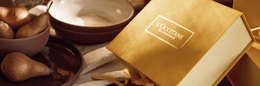 L'Occitane en Provence Geschenkbox in Gold vor beigem Hintergrund