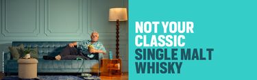 Ein älterer Mann entspannt auf einem stilvollen blauen Sofa, hält einen Drink in einer Ananas-Tasse und genießt seine Zeit. Daneben steht eine Flasche Bruichladdich Whisky. Der Slogan "NOT YOUR CLASSIC SINGLE MALT WHISKY" ist prominent zu sehen.