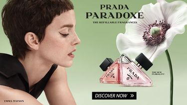 Prada Paradoxe ad featuring Emma Watson with a pixie cut. Two triangular perfume bottles are displayed on a green background with a white flower. Text reads 'Prada Paradoxe, the refillable fragrances' and 'The New Florality.'