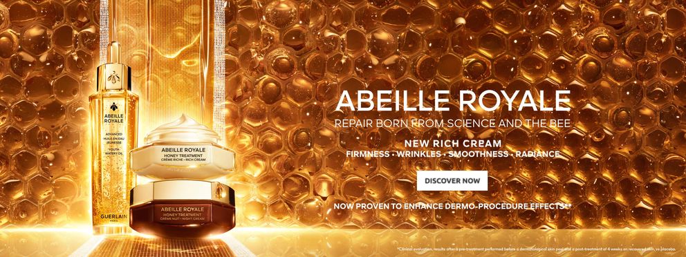  The image is an advertisement for Guerlain's "Abeille Royale" skincare line, showing a dropper bottle and cream jar against a honeycomb background, highlighting the product's honey-inspired ingredients and benefits for skin firmness, wrinkle reduction, a