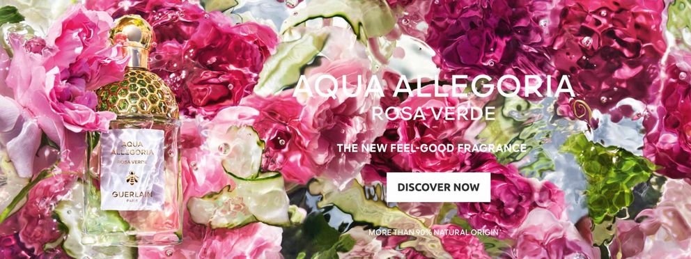 Bottle of Guerlain perfume "Rose Verde" from the Aqua Allegoria collection, surrounded by pink rose petals and cucumber slices. Text on the image: "Aqua Allegoria Rose Verde - The New Feel-good Fragrance. More than 90% natural origin.